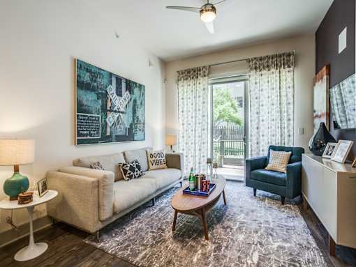 A living room with a couch, a chair, a coffee table, and a painting on the wall.