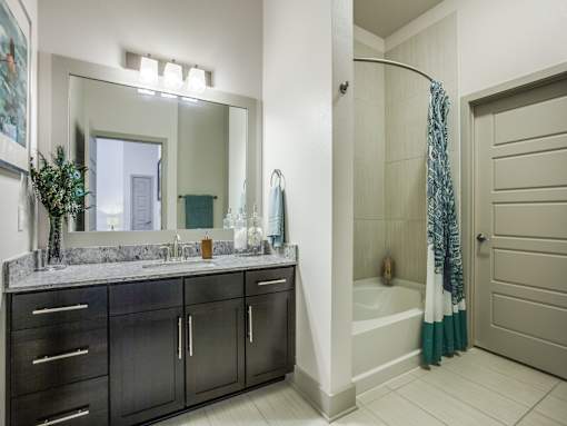 A bathroom with a large mirror, a sink, and a shower.