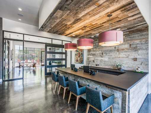 A modern kitchen with a wooden ceiling and a long island with chairs.