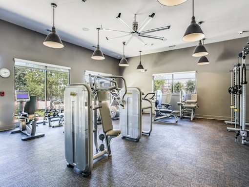 A gym with a variety of equipment including treadmills, weights, and exercise machines.
