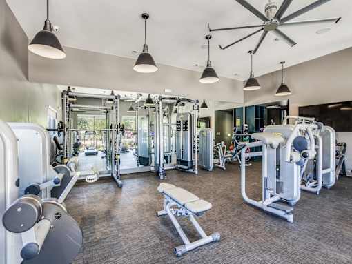 A spacious gym with a variety of equipment and a ceiling fan.