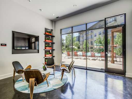 A living room with a large window and a view of a pool area.