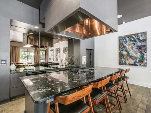 A modern kitchen with a large island and wooden chairs.