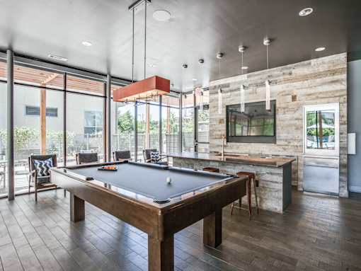 A pool table in a room with a stone wall and a bar.