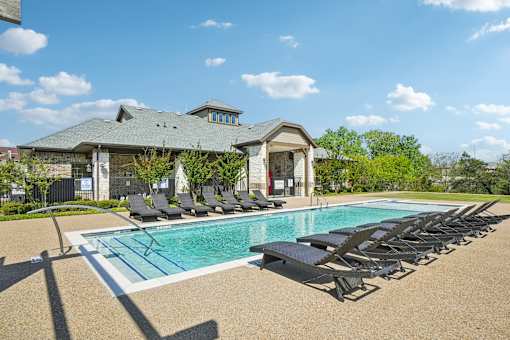 A pool with sun loungers and a building in the background.