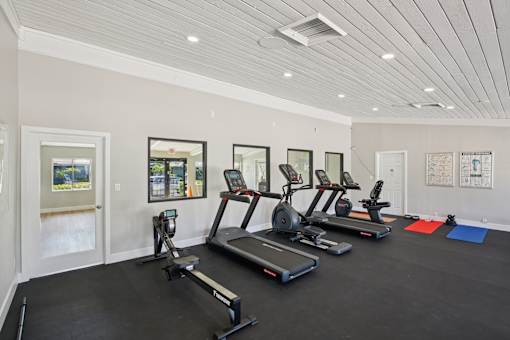 A spacious gym with treadmills, exercise bikes, and yoga mats.