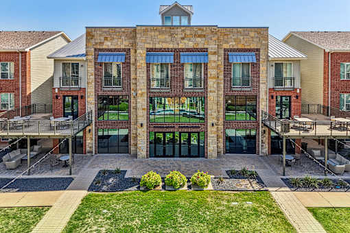 A large building with a brick facade and a green lawn in front.