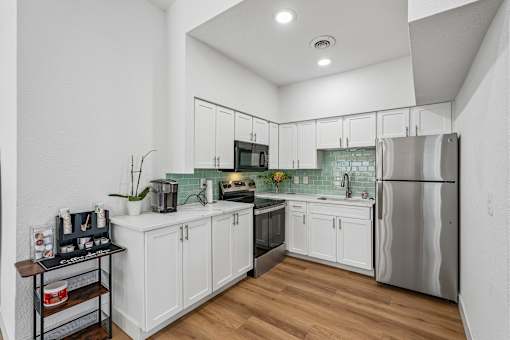 A kitchen with white cabinets and a stainless steel refrigerator.