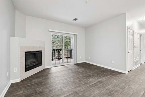 A living room with a fireplace and a view of trees outside the window.