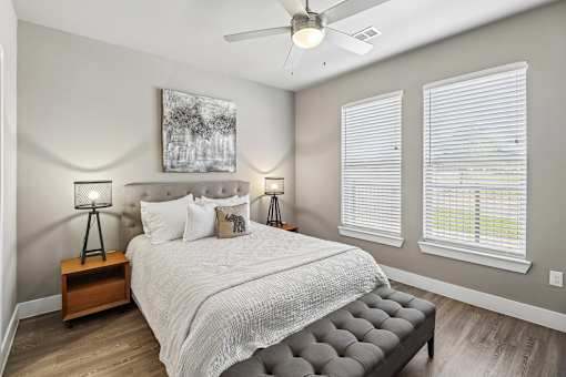 A bedroom with a large bed, a ceiling fan, and two lamps.