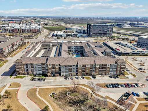 A large apartment complex with a parking lot in front.