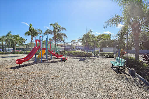 A playground with a red slide and green bench.