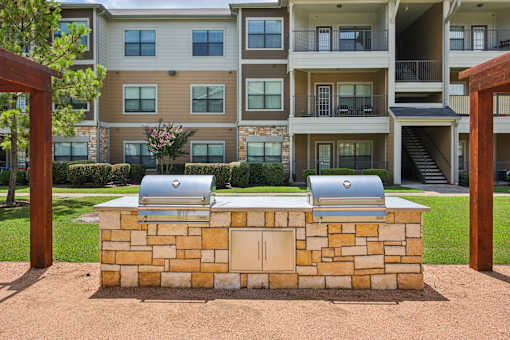 A stone wall with two grills on top of it.