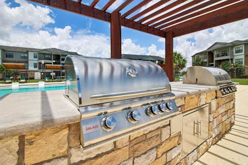 A stainless steel grill is built into a stone wall.