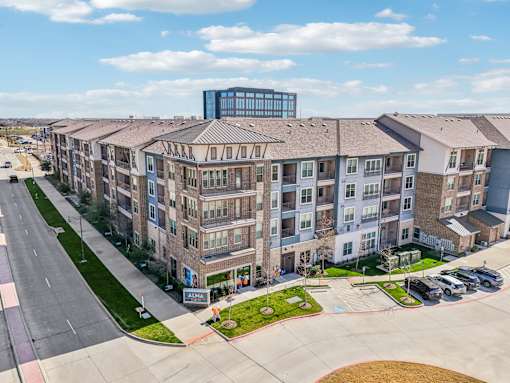 A large apartment complex with a parking lot in front.