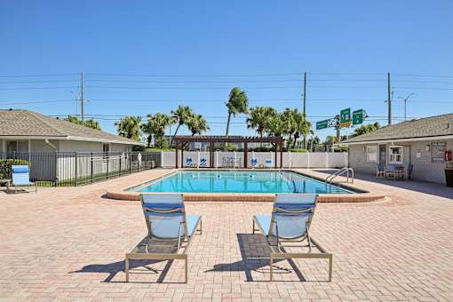 A pool with two chairs in front of it.
