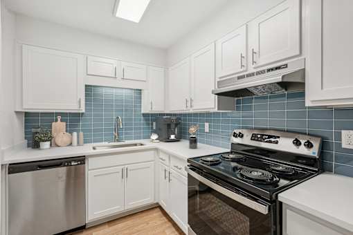 A kitchen with white cabinets and a black stove top oven.