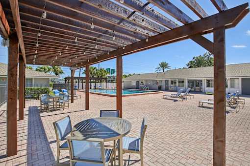 A patio with a table and chairs under a wooden pergola.