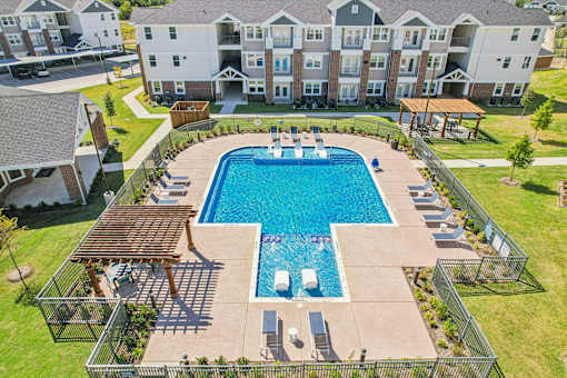 A large swimming pool surrounded by a fence and a building in the background.
