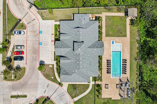 A large grey building with a pool in front of it.