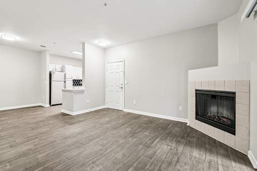 A living room with a fireplace and a refrigerator in the corner.
