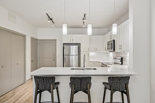 A kitchen with a white countertop and a refrigerator in the middle.