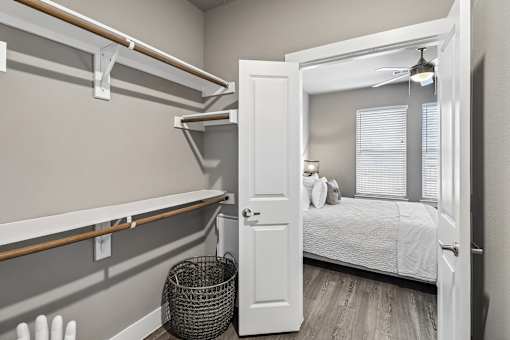 A bedroom with a bed, a window with blinds, and a basket on the floor.
