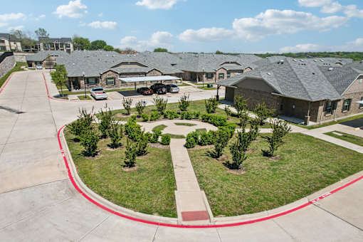 A large building complex with a red line around the grassy area in the foreground.
