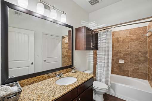 A bathroom with a sink, toilet, and a large mirror.