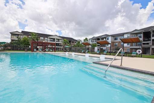 A large swimming pool in front of apartment buildings.
