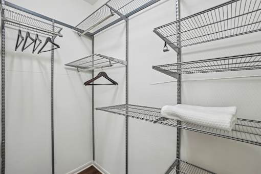 A white closet with a metal shelf and a white towel hanging on it.