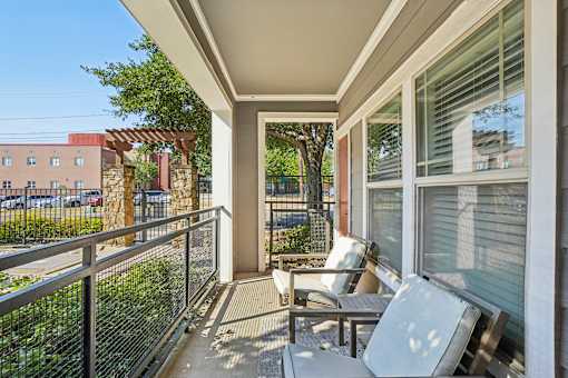 A patio with a table and chairs overlooks a parking lot.