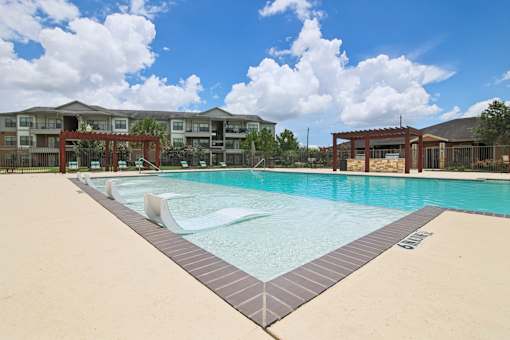 A large swimming pool in front of apartment buildings.