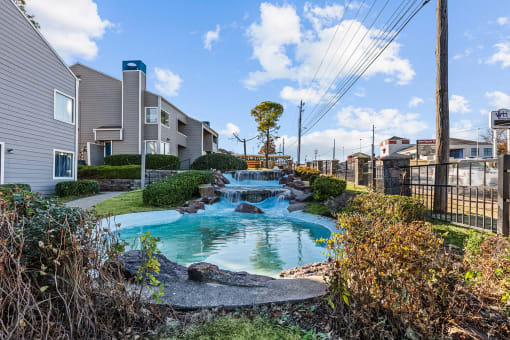 a small pool with waterfalls in front of apartment buildings