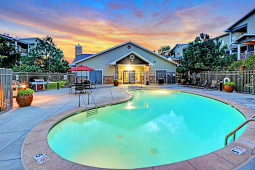 A swimming pool surrounded by a fence and a house in the background.