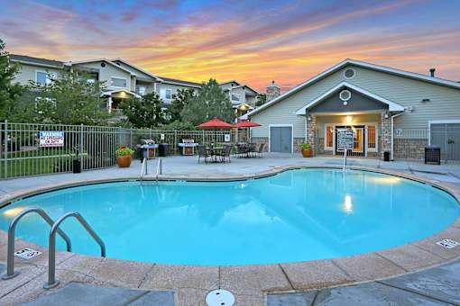 A swimming pool in a backyard with a sunset in the background.