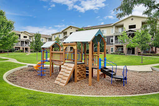 A playground with a wooden swing set and a blue slide.