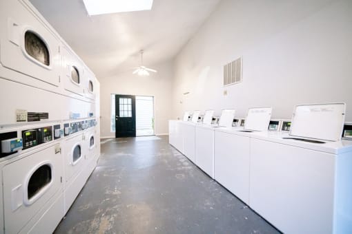 a washer and dryer room with a row of washes and dryers