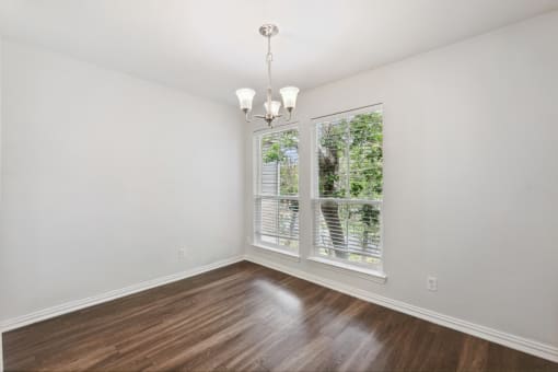 an empty living room with a large window and wooden floors