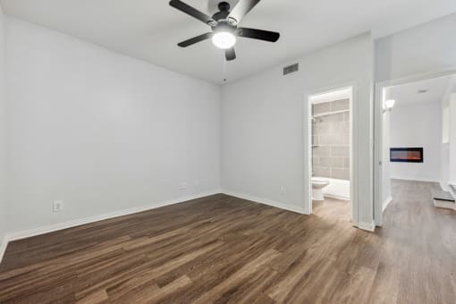 an empty living room with a ceiling fan and a bathroom