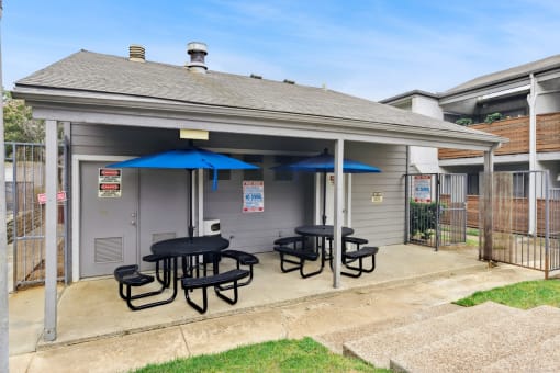 a patio with tables and umbrellas outside of a house