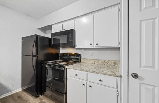 a kitchen with white cabinets and a black stove and refrigerator
