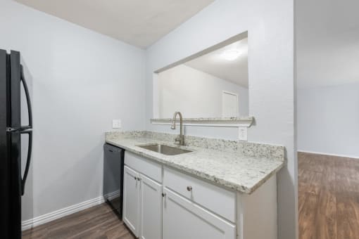 a kitchen with white cabinets and a counter top with a sink