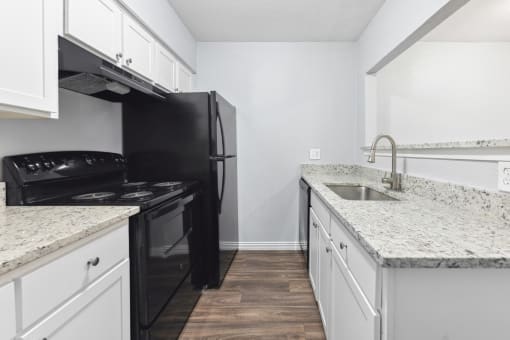 an empty kitchen with white cabinets and a black stove and refrigerator