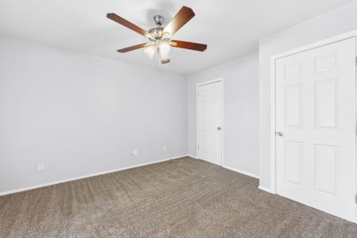 an empty living room with a ceiling fan