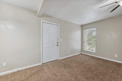 an empty living room with a white door and a window