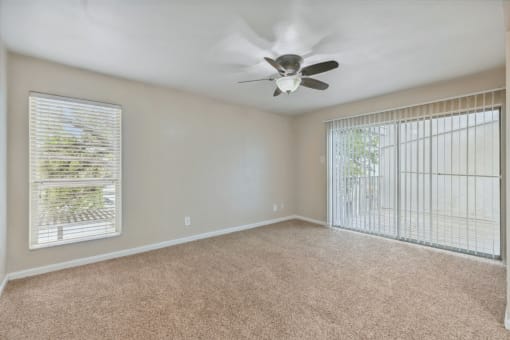 an empty living room with a ceiling fan and a window