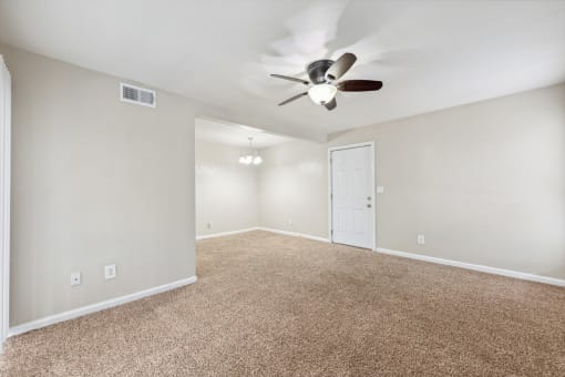 the spacious living room with ceiling fan and carpet