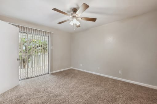 an empty living room with a ceiling fan and a window