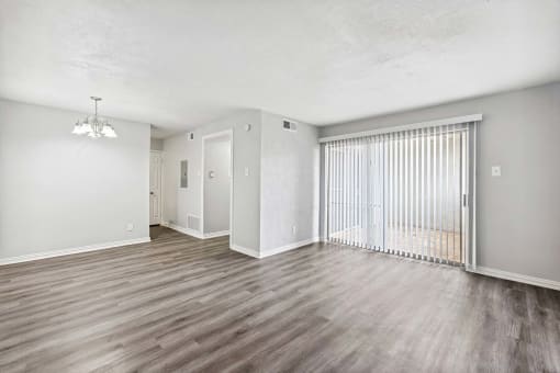 an empty living room with a sliding glass door to a balcony